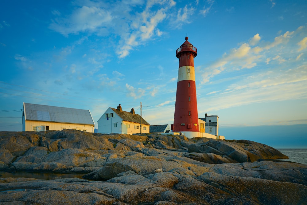 a red and white lighthouse sitting on top of a rocky shore