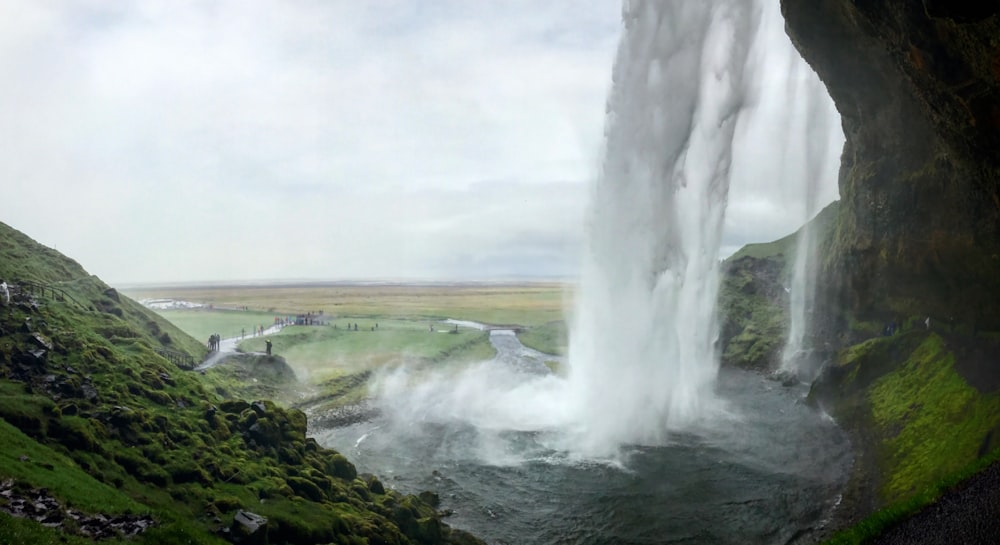 a large waterfall is in the middle of a green valley