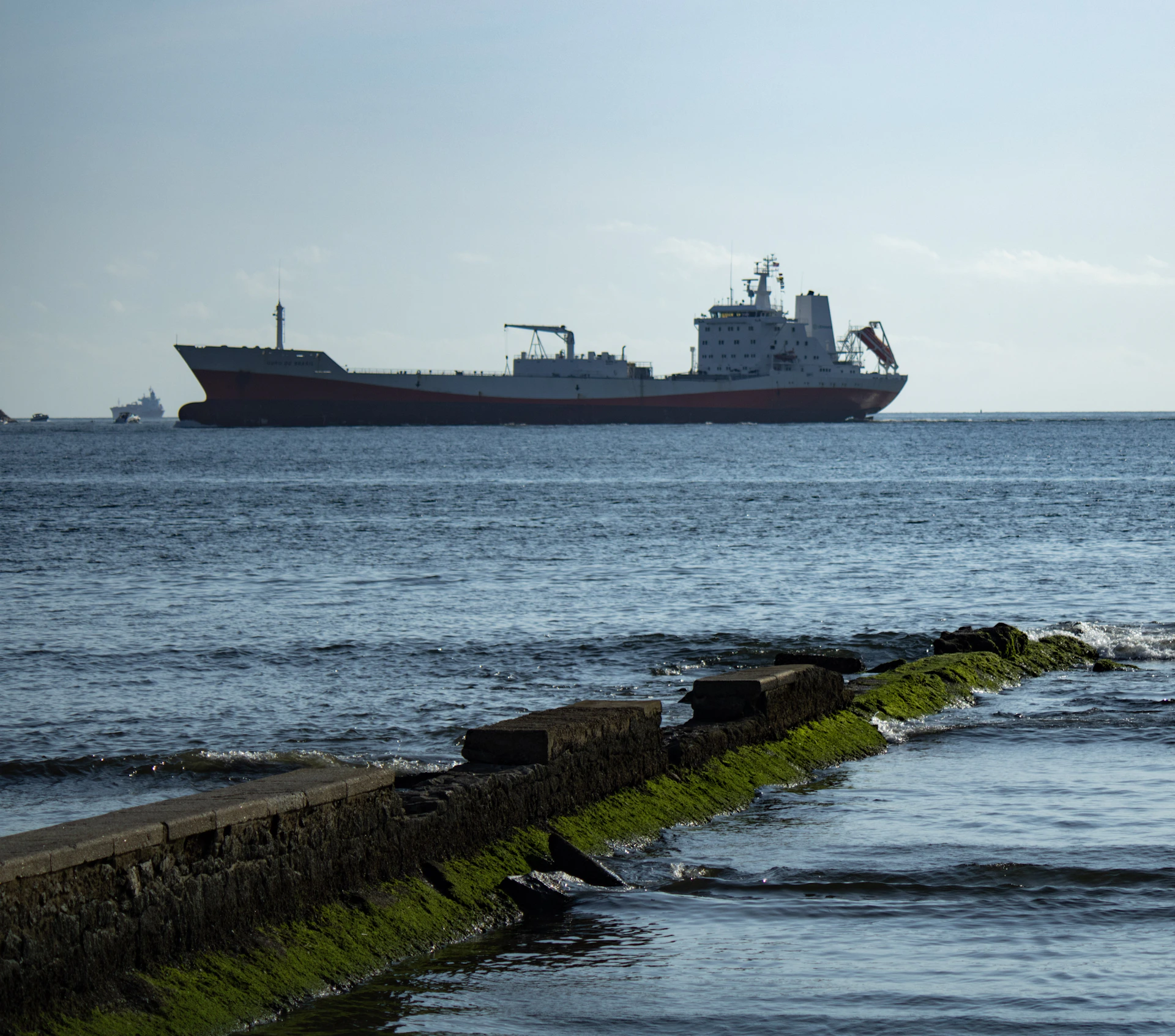 a large cargo ship in the ocean near a break wall