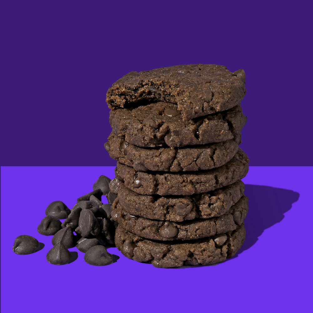 a stack of cookies and chocolate chips on a purple and blue background