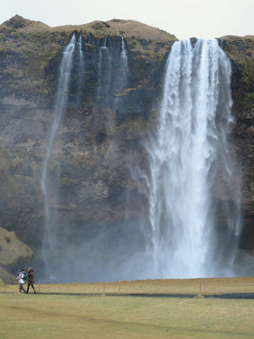 a couple of people that are standing in front of a waterfall