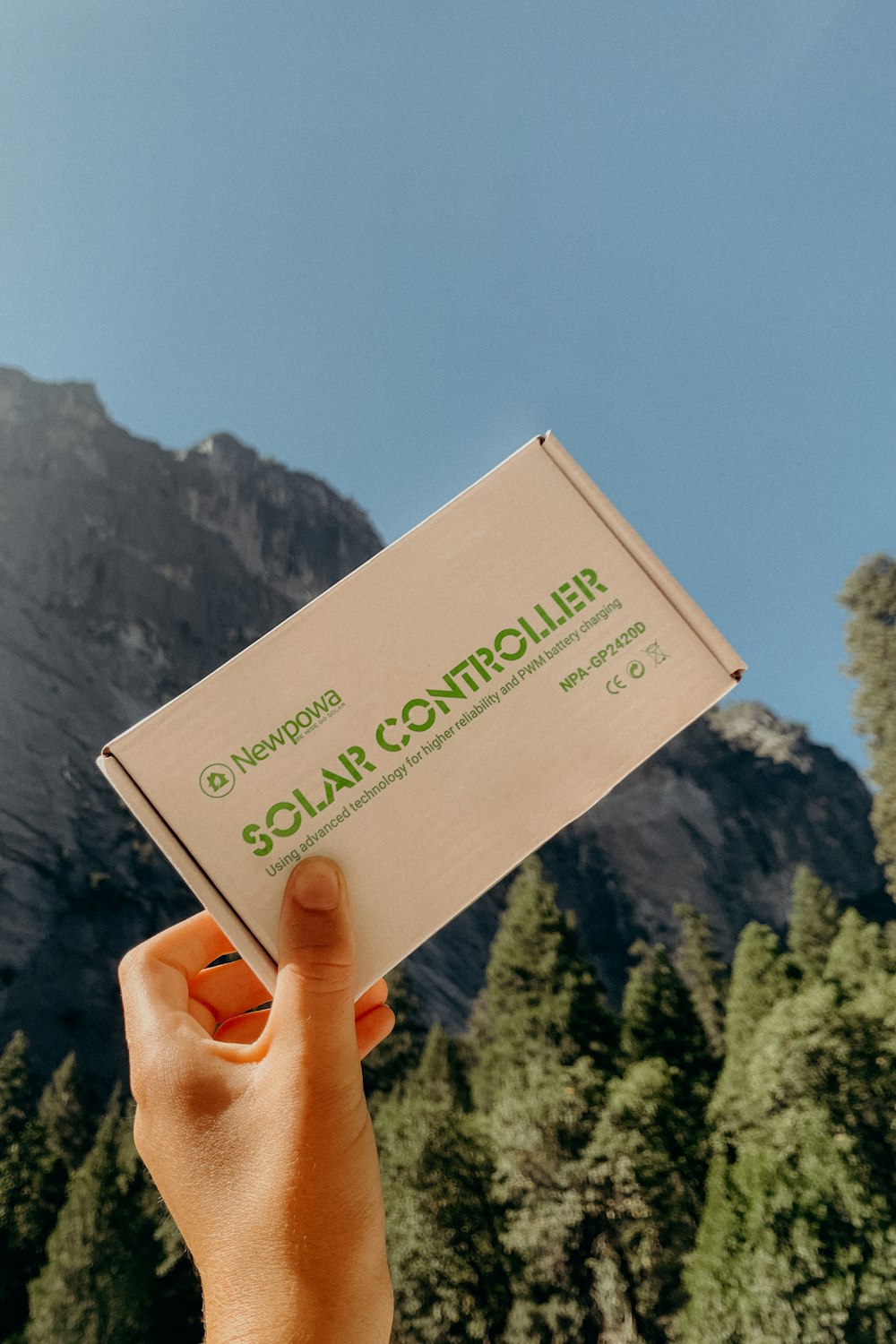 a hand holding a box of soap in front of a mountain