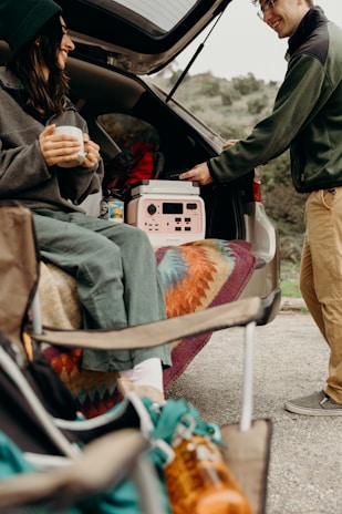 Traveler enjoying a warm drink while charging their electric vehicle outside a sip of joy location