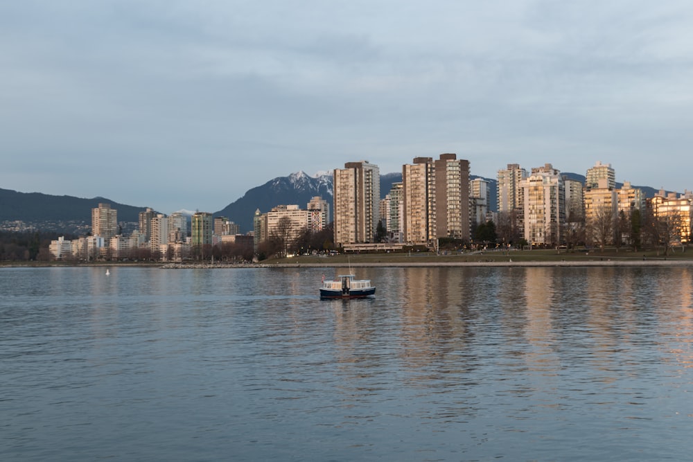 a boat floating on top of a lake next to tall buildings