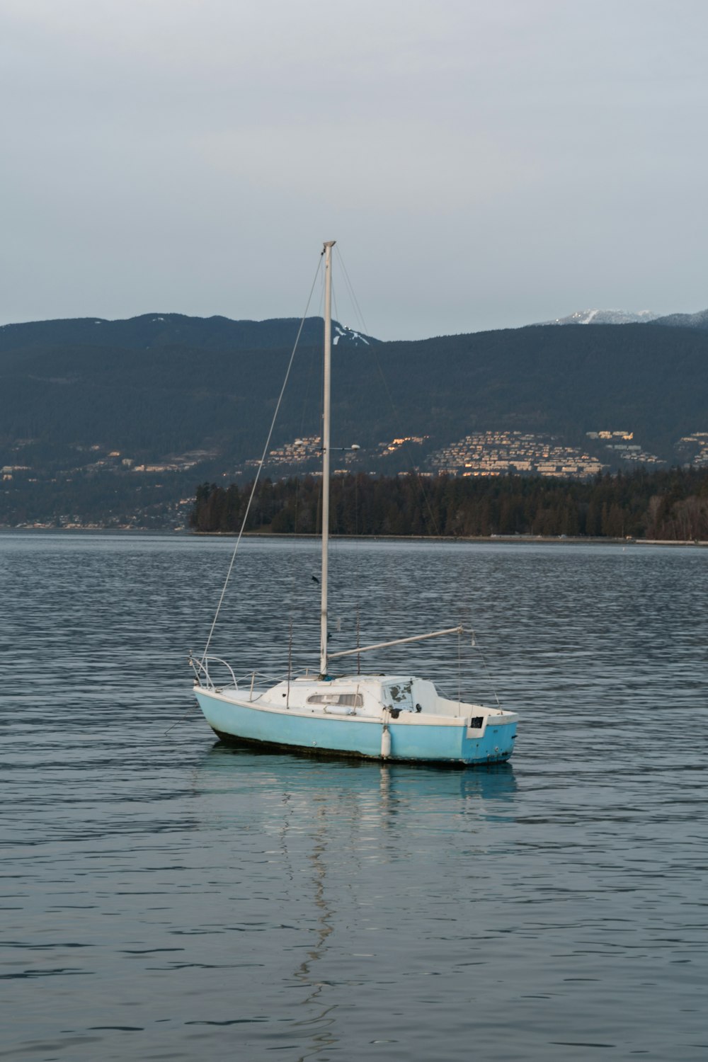 a sailboat floating on a lake with mountains in the background