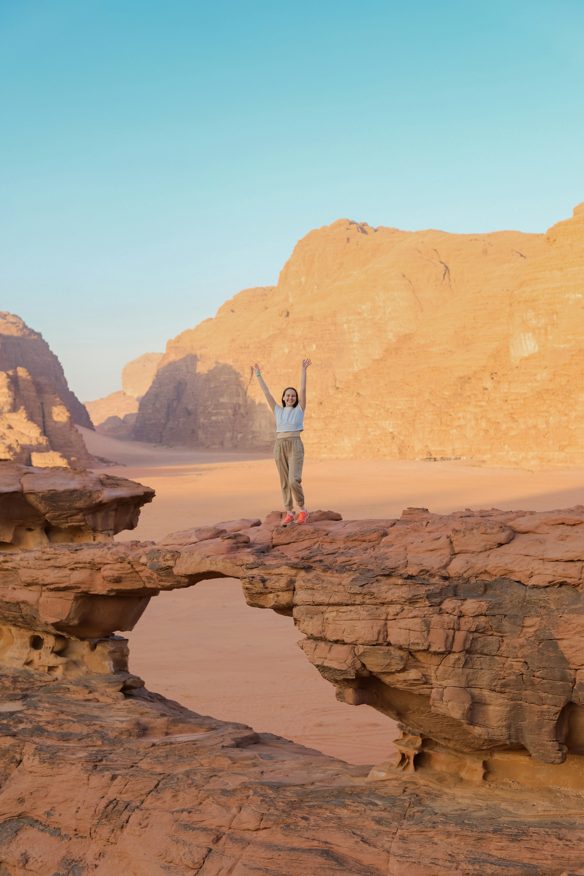 a woman standing on a rock formation with her arms in the air