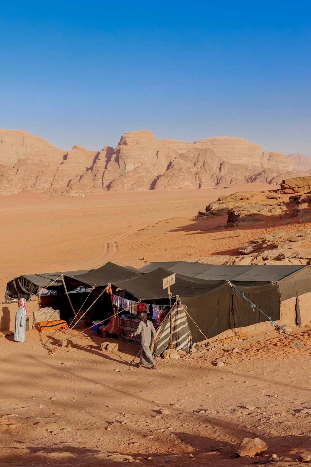 a tent in the middle of a desert with mountains in the background