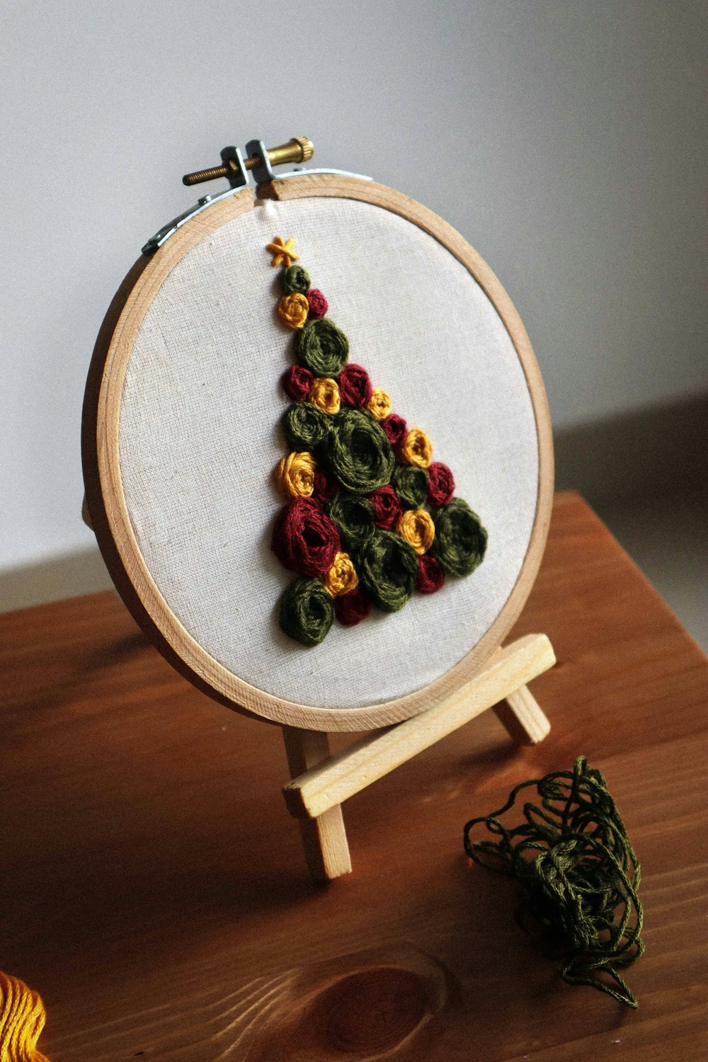a cross stitch christmas tree on a wooden stand