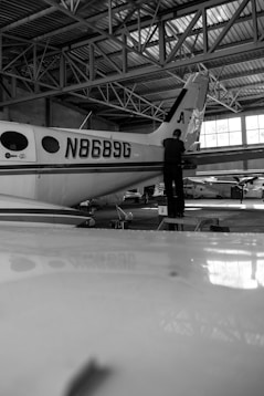 a black and white photo of a man standing next to an airplane