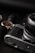A close-up of a vintage camera alongside a wristwatch with a black leather strap and a gold casing. The image features a primarily dark background with a sense of elegance and sophistication.