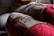 Two intricately patterned cushions with rich red fabric and detailed embroidery rest on a soft surface, creating a cozy and inviting atmosphere in what appears to be a living space with soft lighting.
