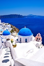 a view of a blue domed building on the edge of a cliff