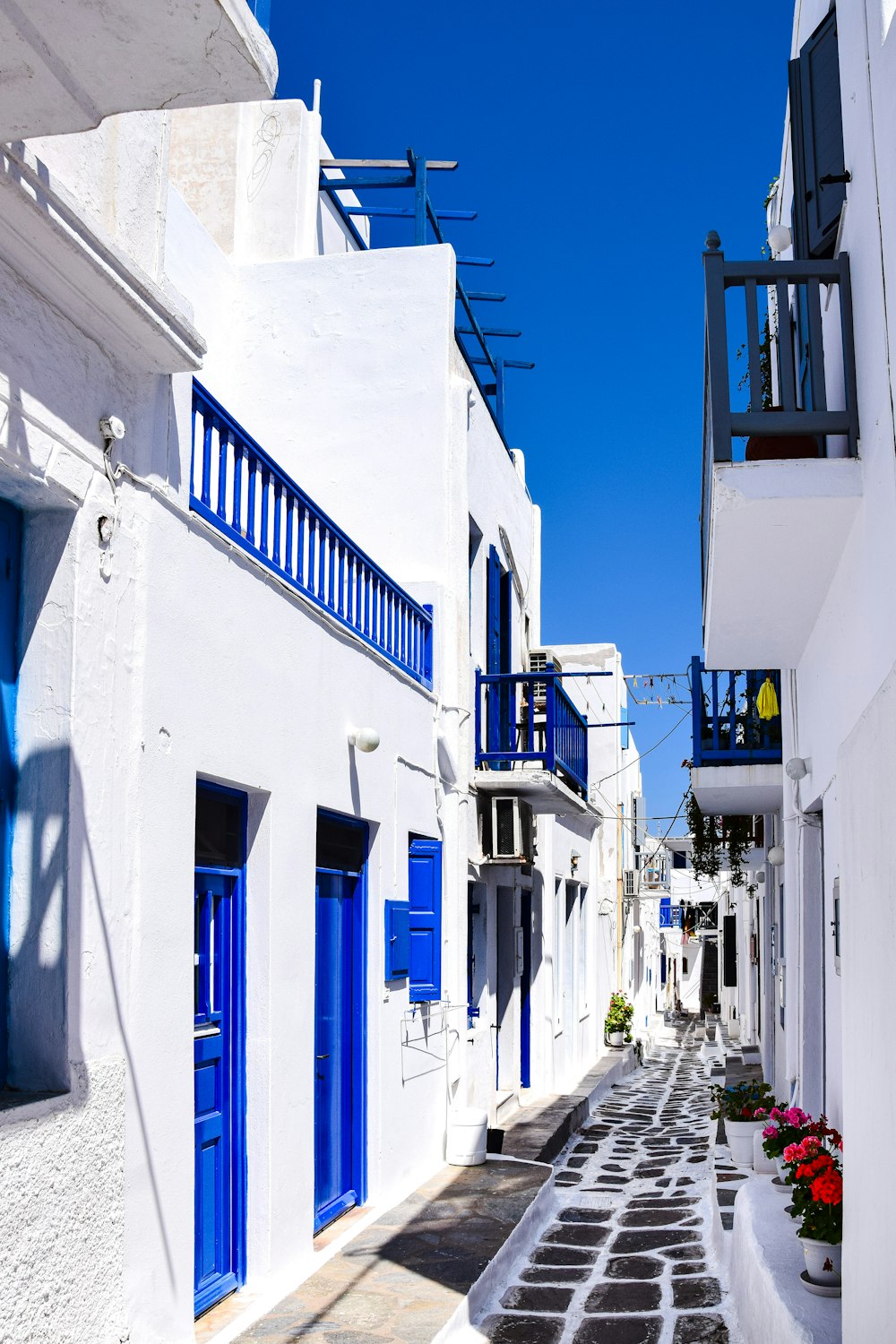 eine schmale Straße mit weißen Gebäuden und blauen Fensterläden