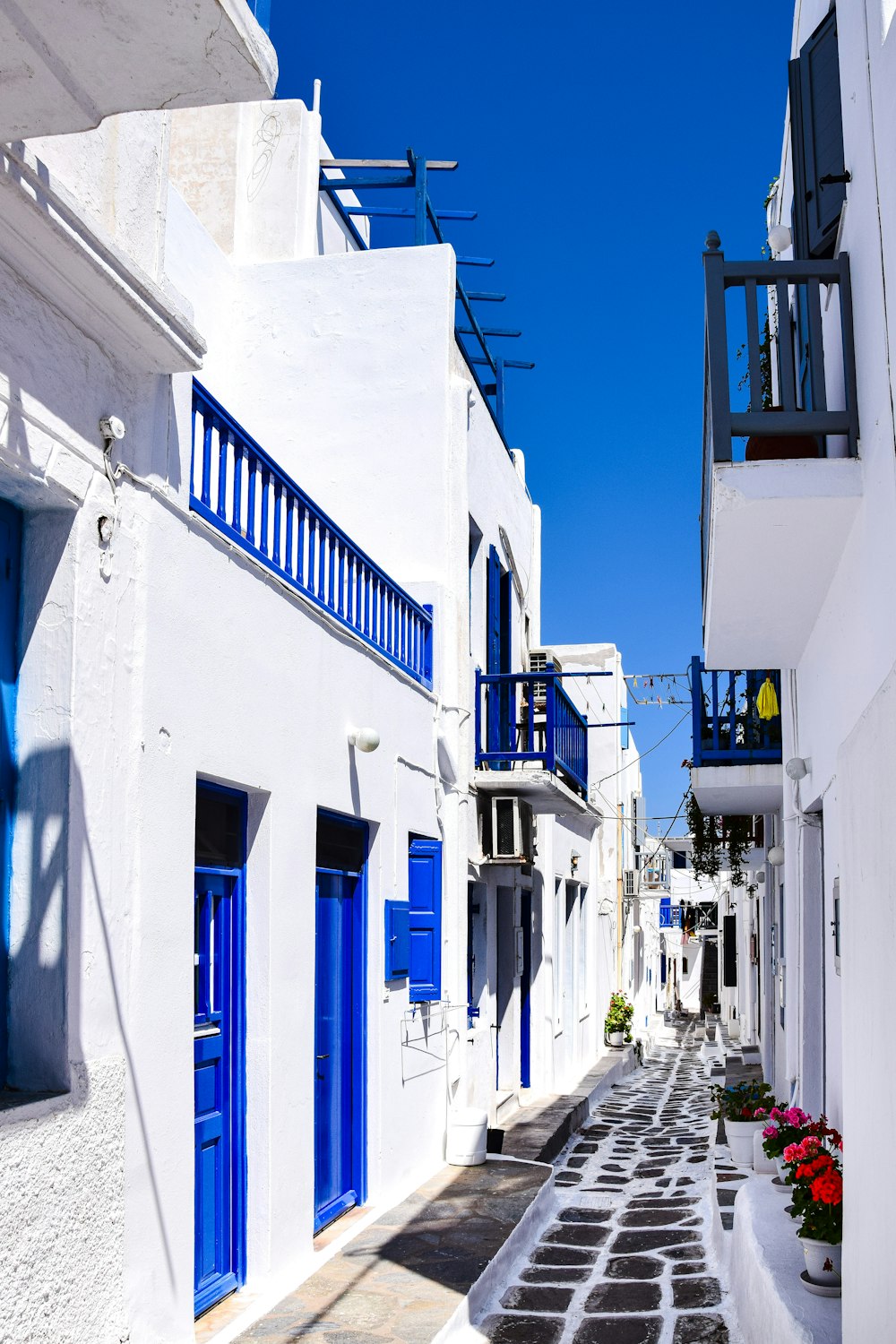 a narrow street with white buildings and blue shutters