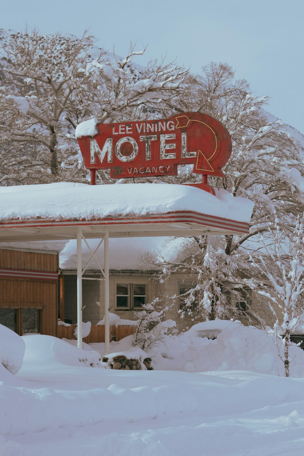 Un cartello di motel coperto di neve davanti agli alberi