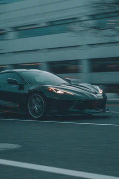 A dynamic photo of a car influencer filming a sleek sports car in an urban setting.