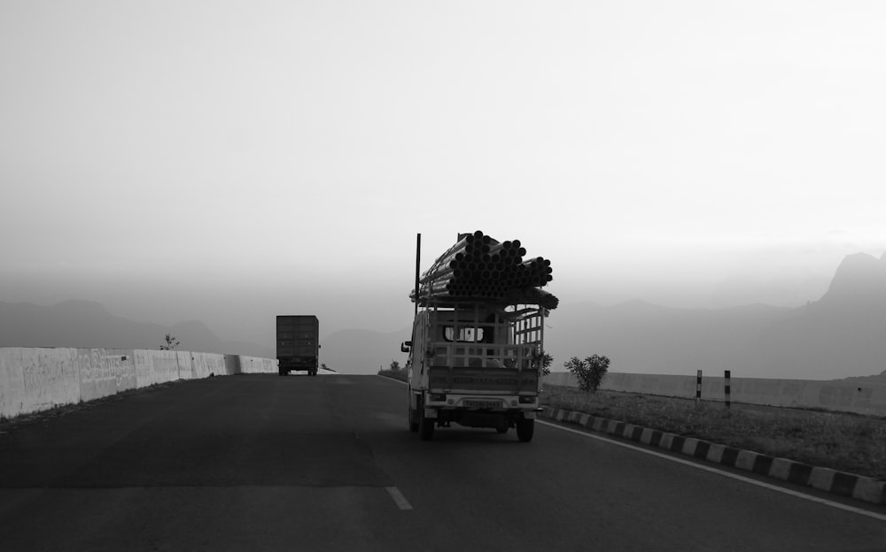 a black and white photo of a truck driving down a road