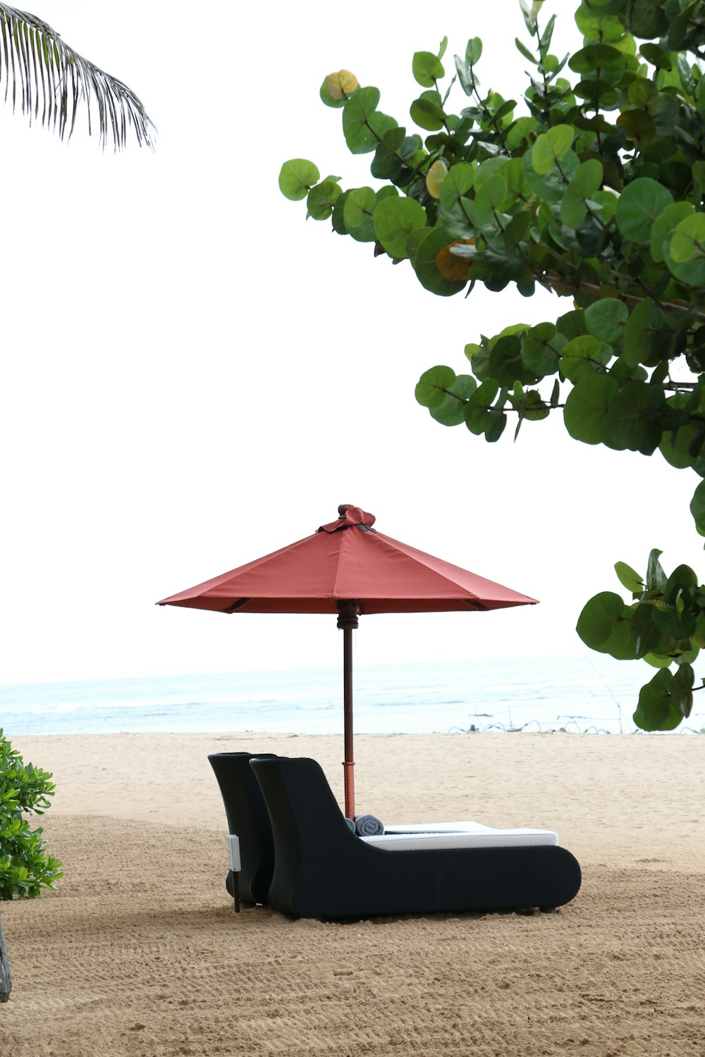 모래 사장 위에 앉아있는 빨간 우산