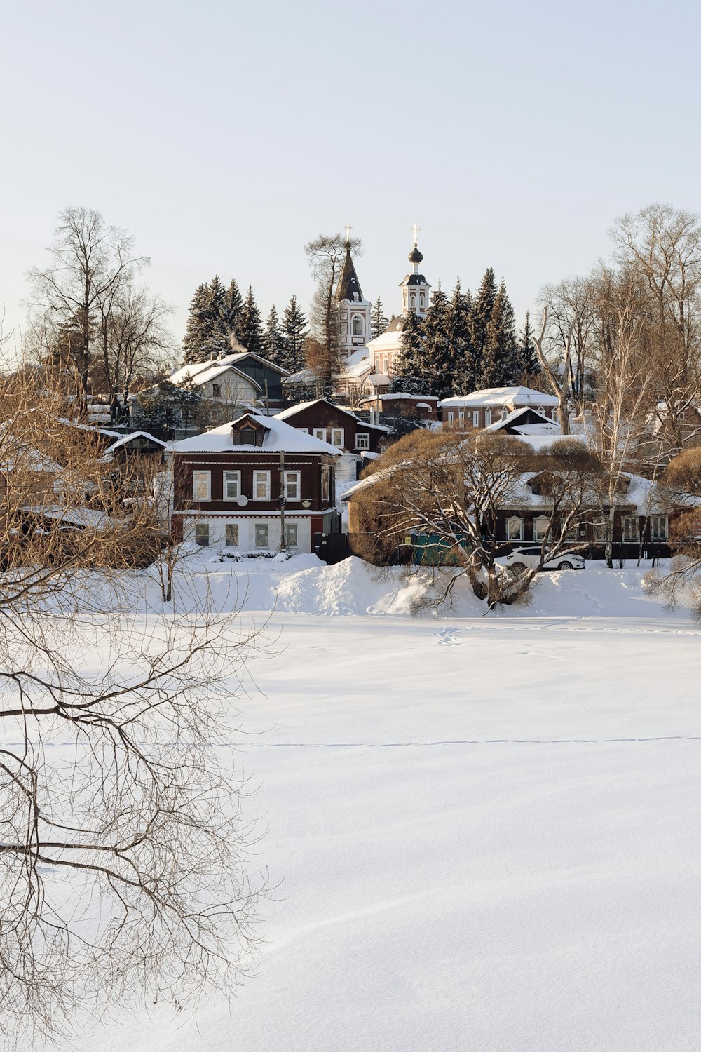 a snow covered field with houses in the background