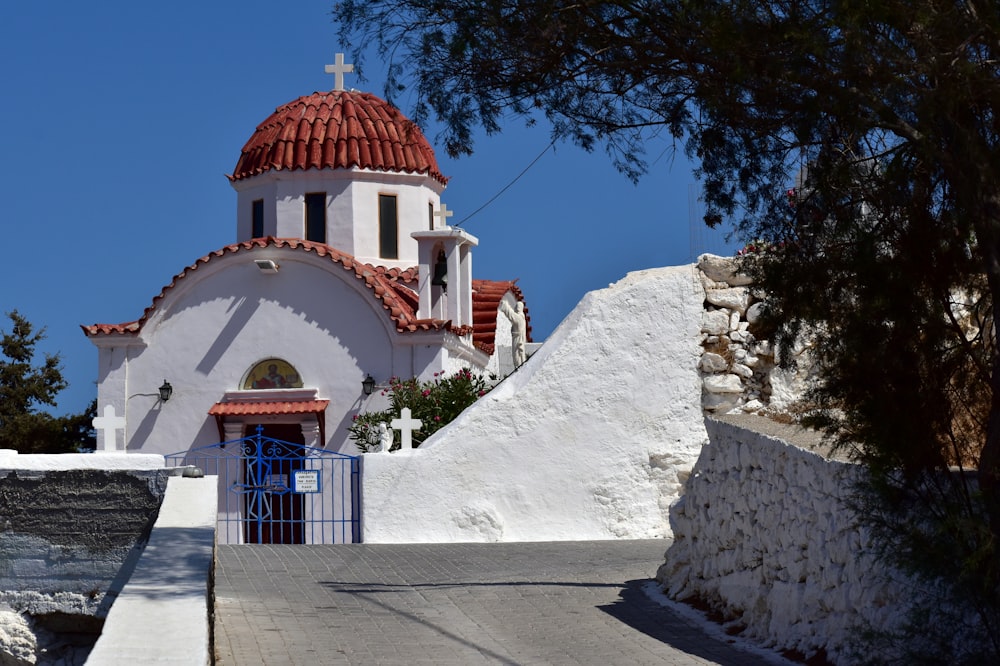 a white church with a red roof and a blue gate