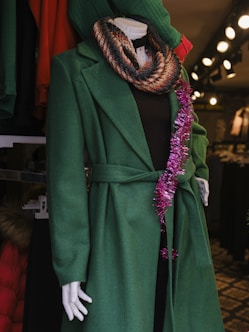 a mannequin dressed in a green coat and scarf