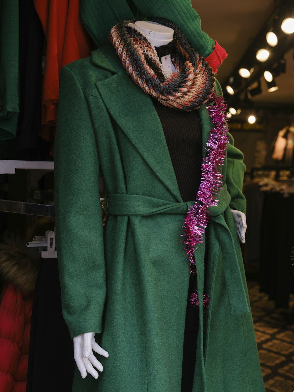 a mannequin dressed in a green coat and scarf