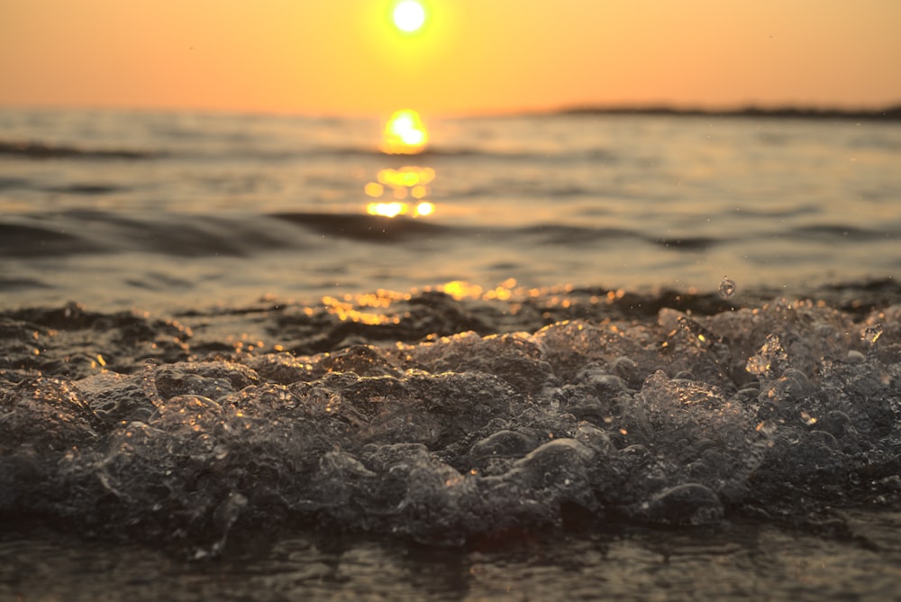 the sun is setting over the ocean waves