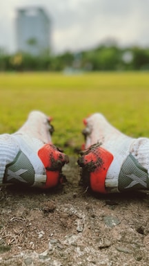 A close-up of a pair of javierm football boots resting on a grassy field under soft sunlight.