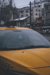 A yellow taxi parked in front of a scenic mountain backdrop.