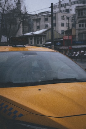 A yellow taxi parked in front of a scenic mountain backdrop.