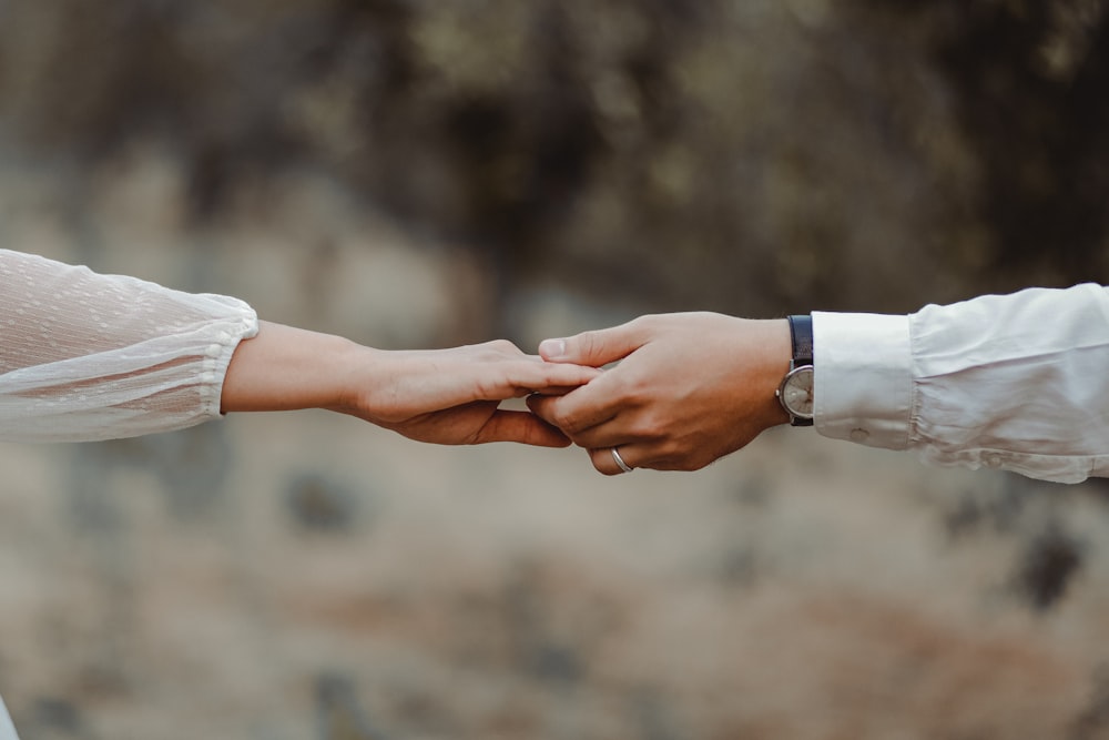 a close up of two people holding hands