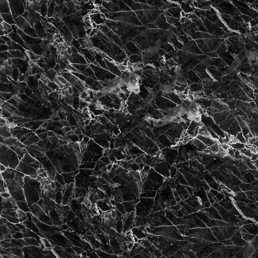 A textured black marble surface with intricate white veining patterns creating a sophisticated and elegant appearance.