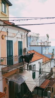 Close-up of traditional terracotta tiles and olive green shutters on a sunny Mediterranean street.