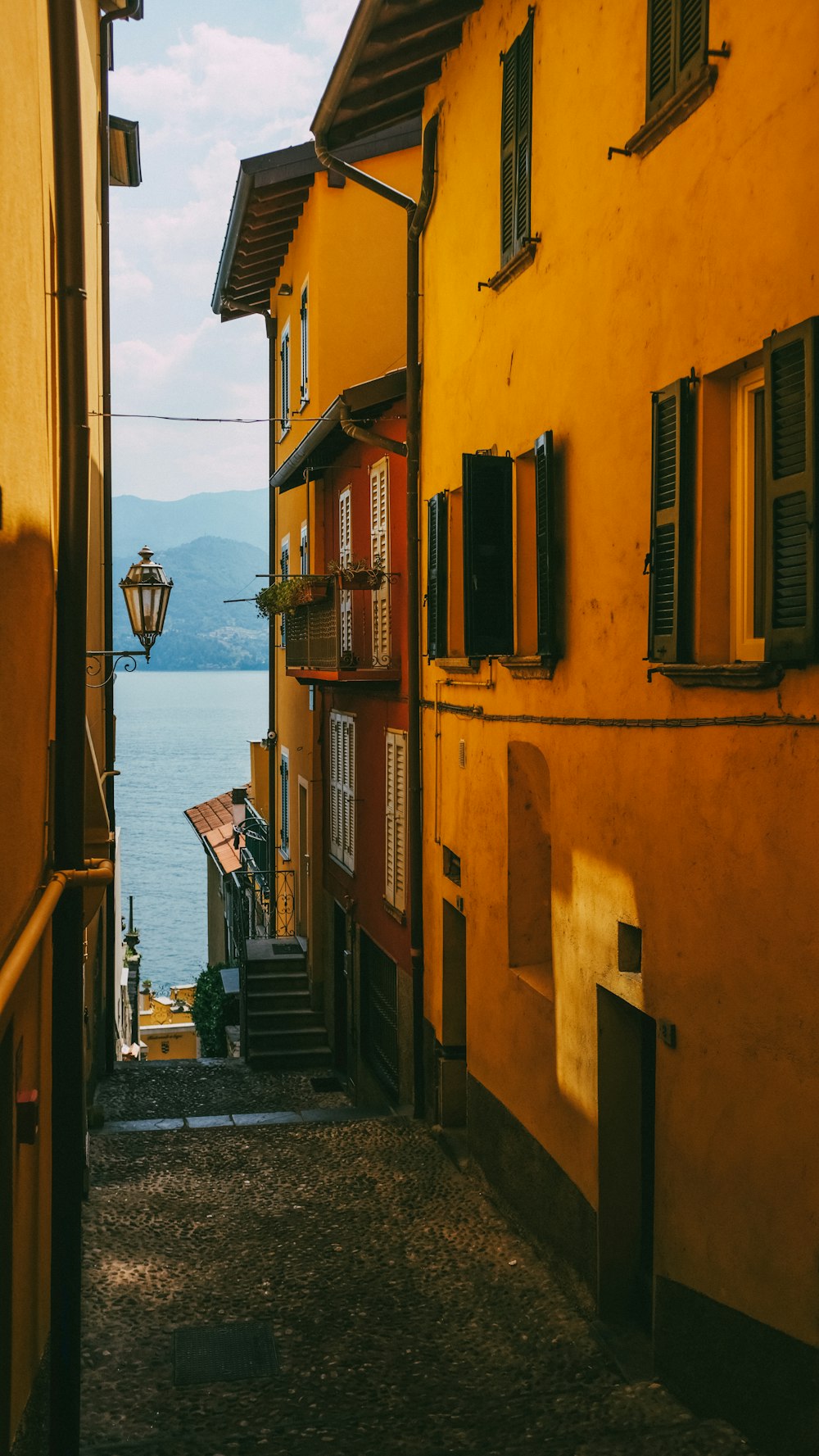 a narrow alley way with a lamp on the side of it