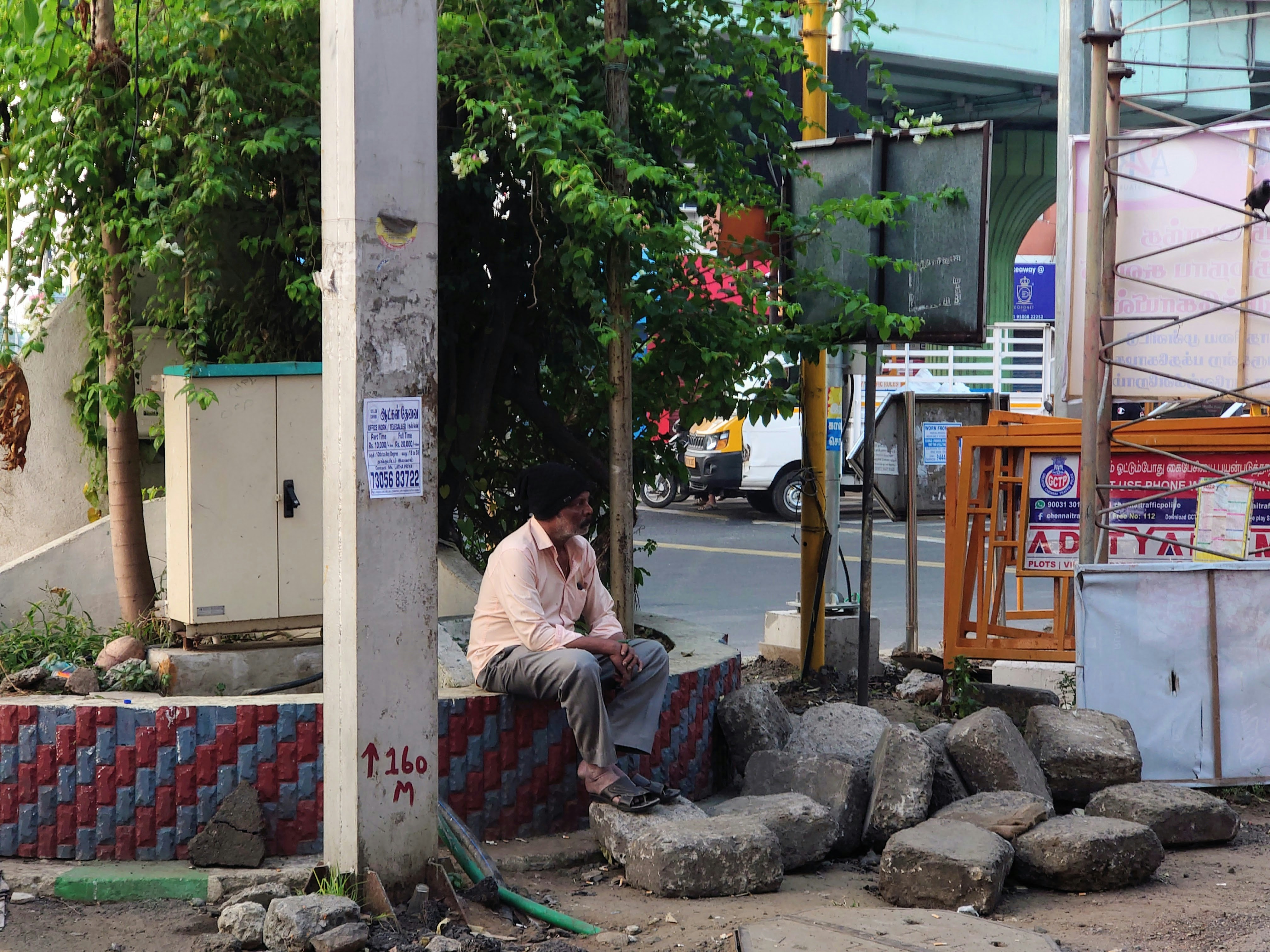 a man sitting on a rock wall talking on a cell phone