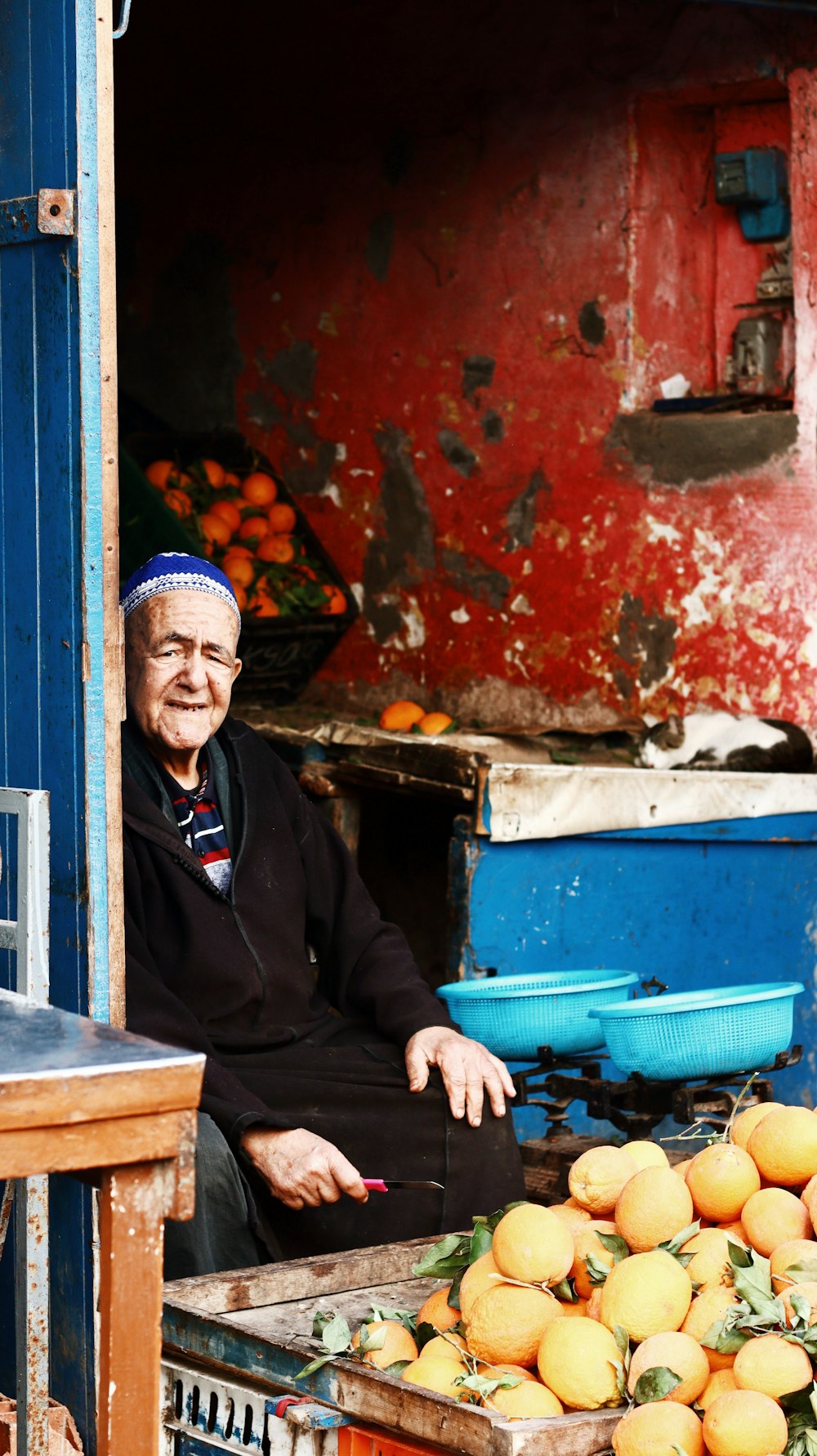 a man sitting on a chair in front of a fruit stand