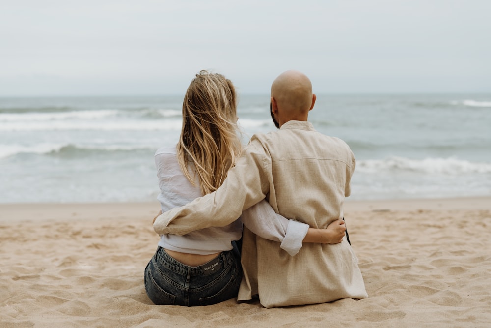 a man and a woman sitting on the beach