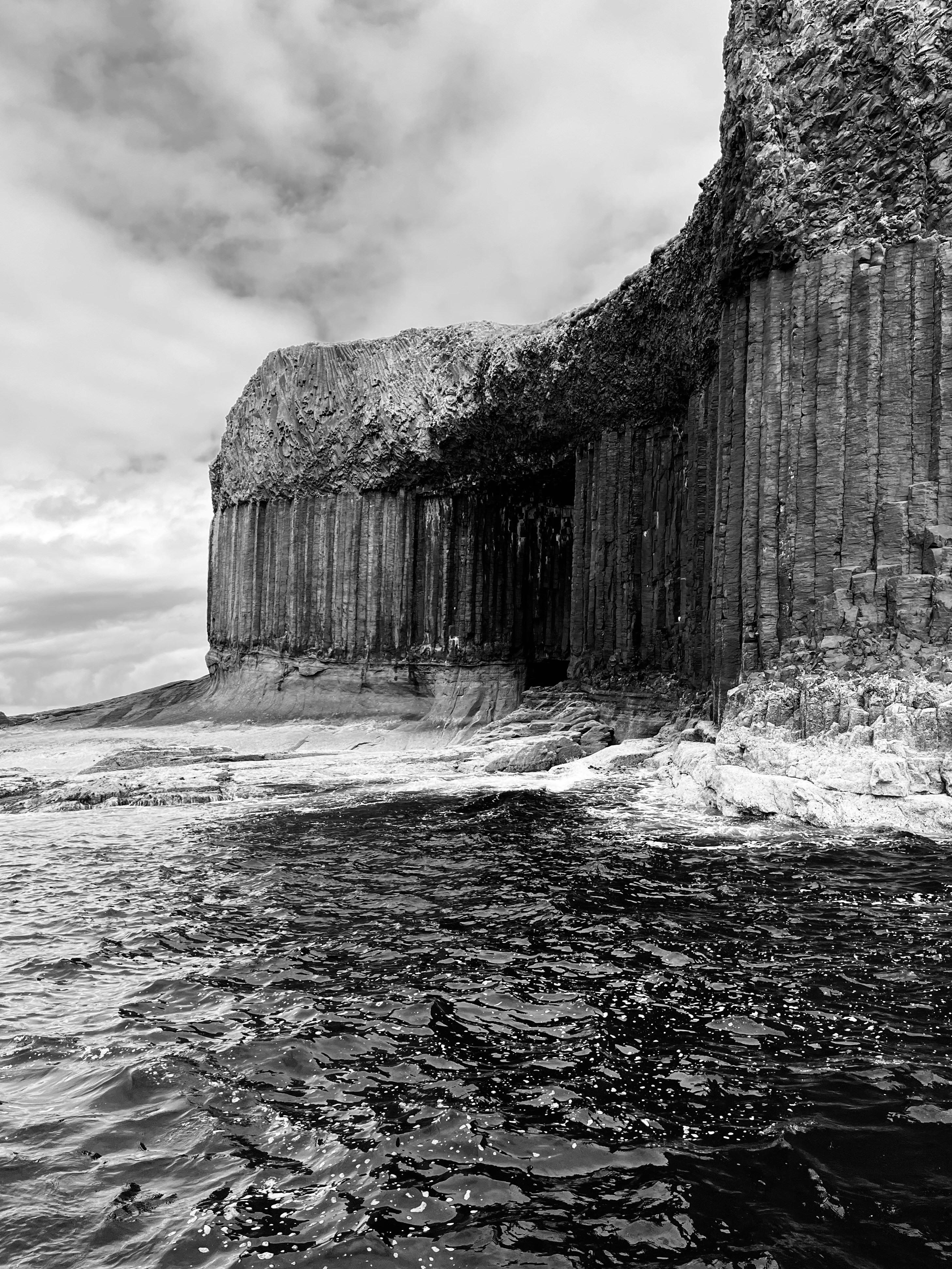 A black and white photo of the ocean and cliffs