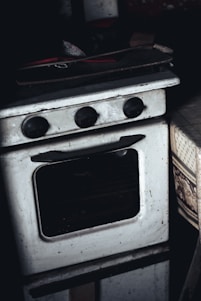 Technician carefully repairing a built-in oven in a modern kitchen setting.