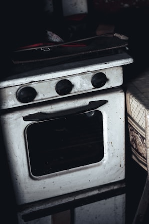 Technician performing maintenance on a built-in oven in a kitchen.