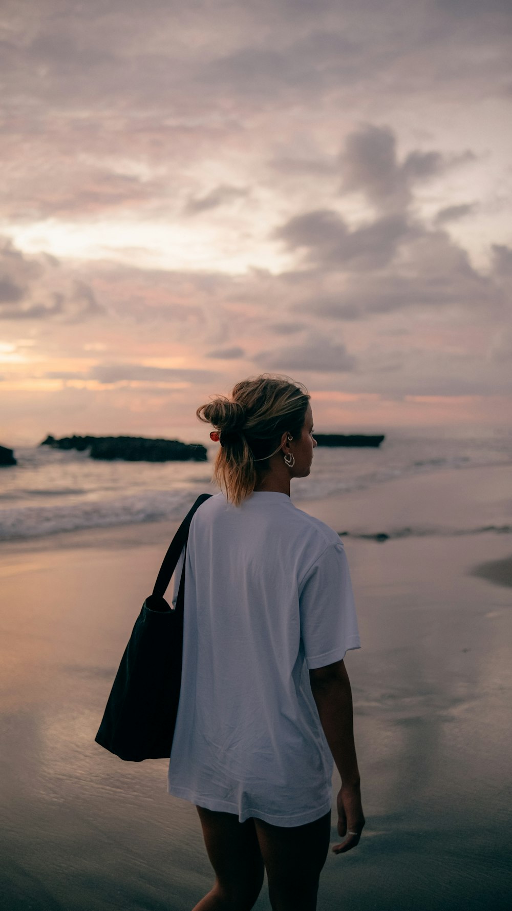 a woman walking on the beach at sunset