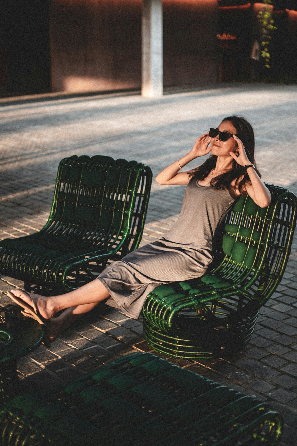 a woman is sitting on a green bench