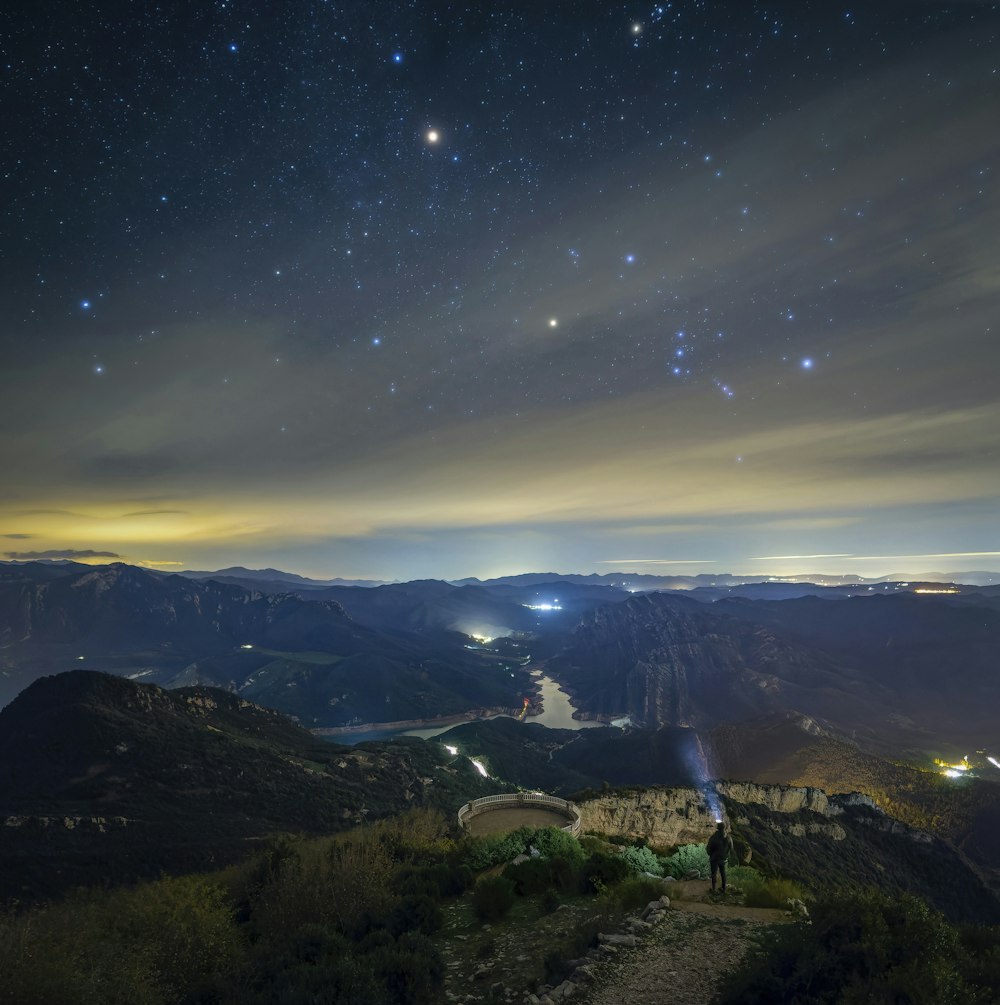 a person standing on top of a mountain under a night sky