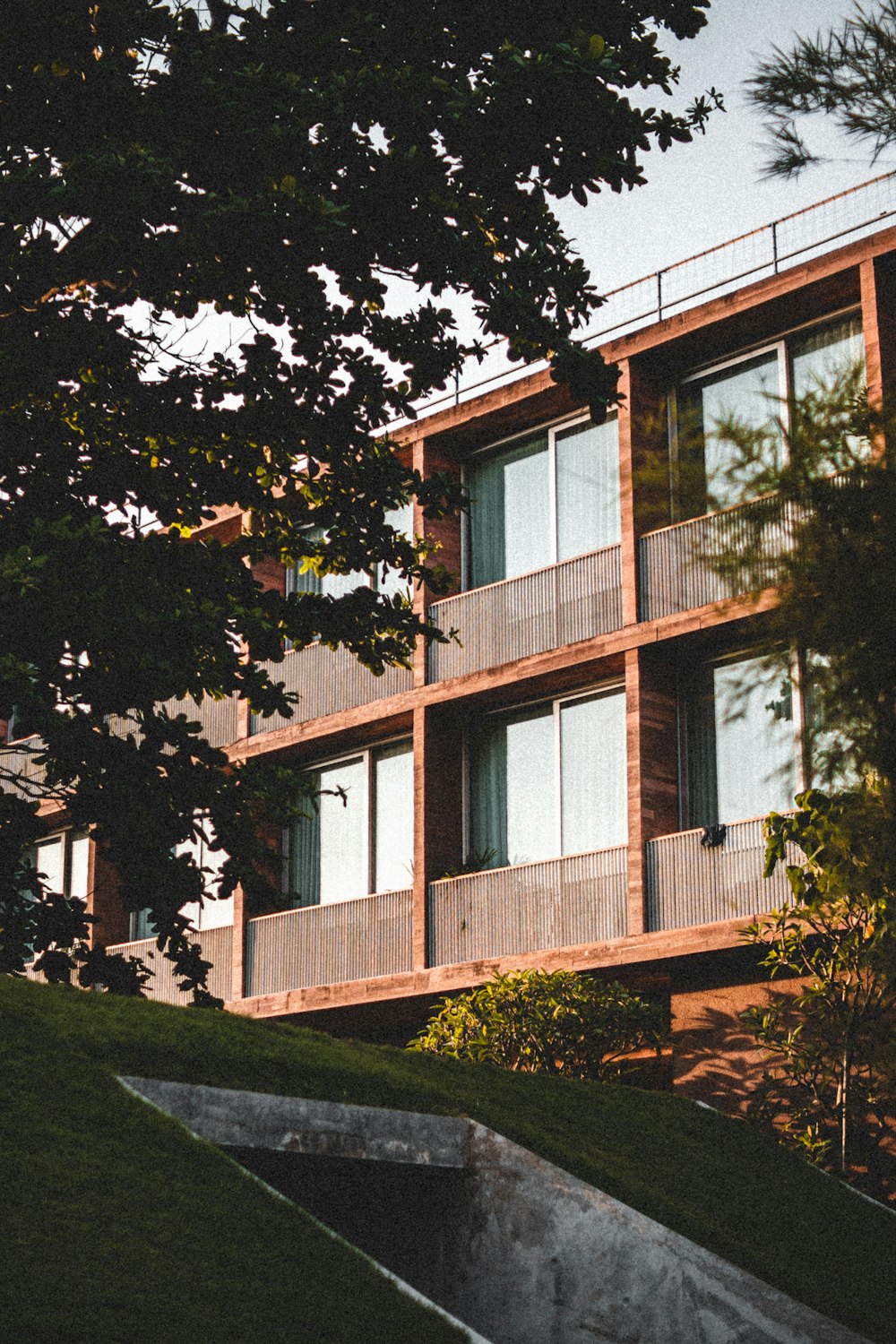 an apartment building with a green lawn and stairs leading up to it