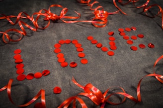 a number of red ribbons and confetti on a gray surface