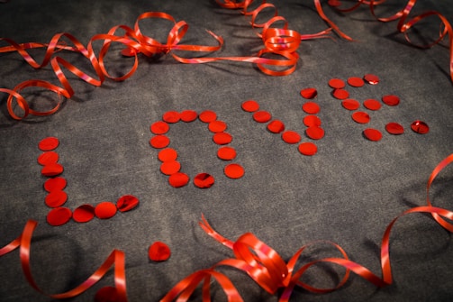 a number of red ribbons and confetti on a gray surface