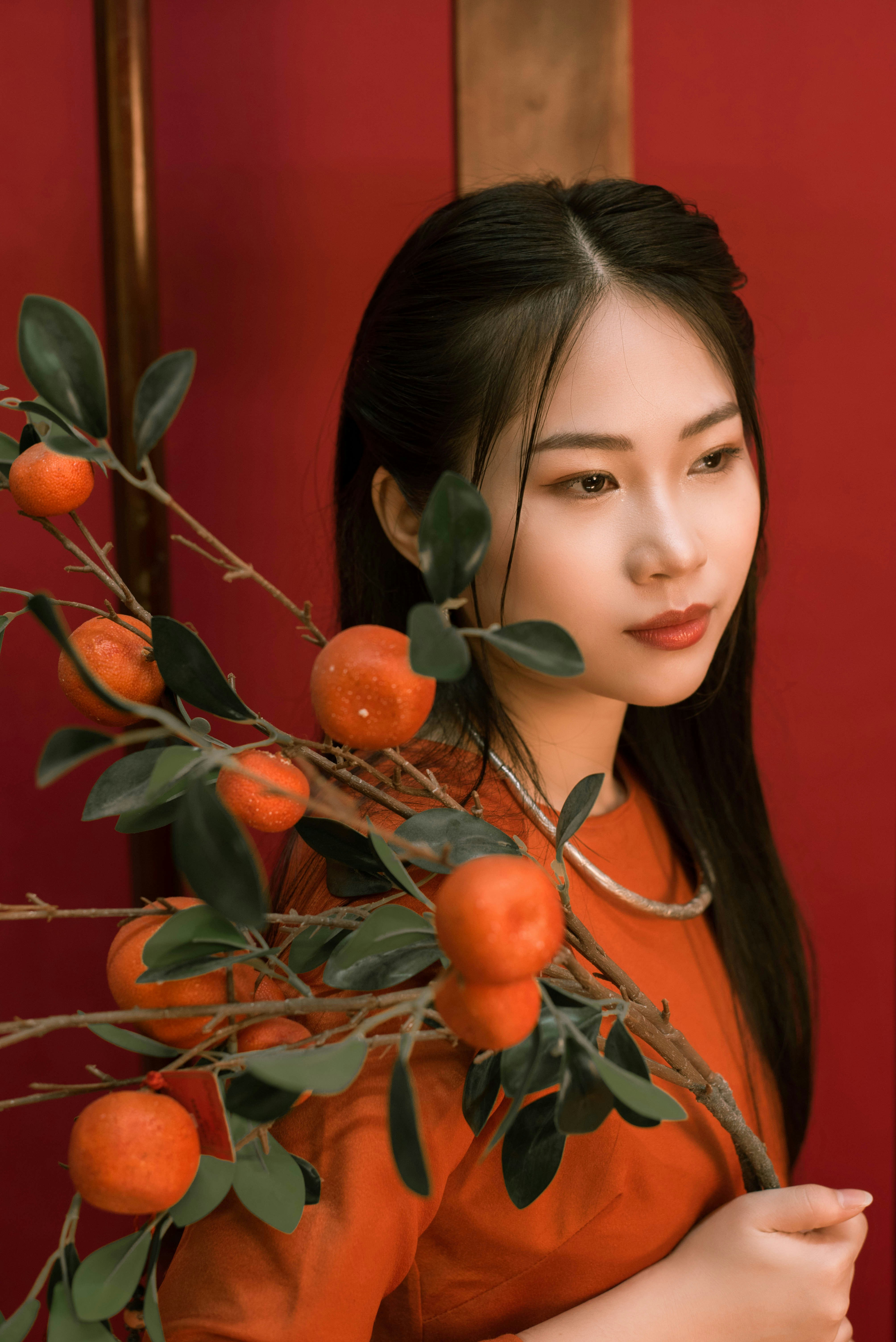 a woman holding a branch with oranges on it
