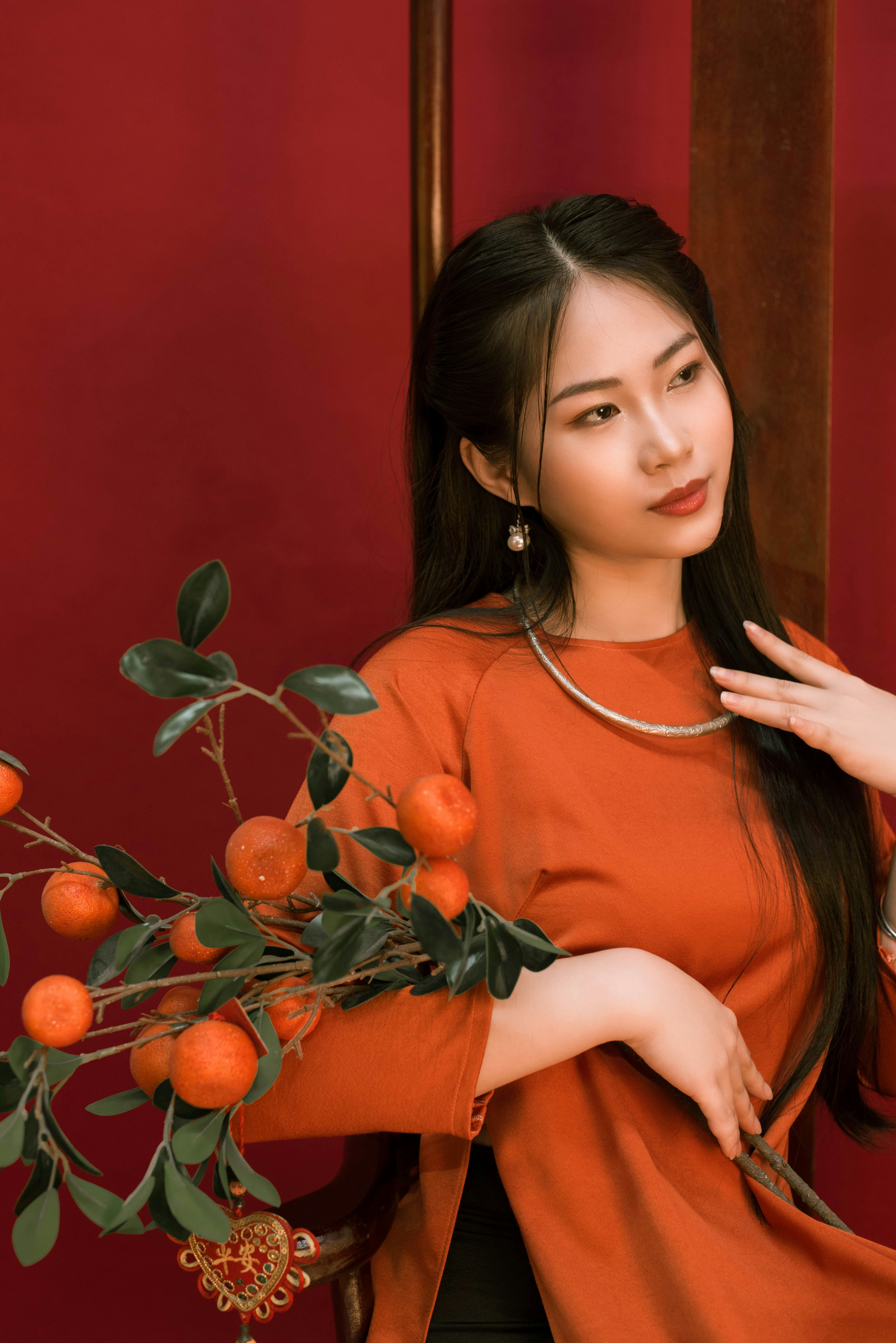 a woman in an orange shirt holding a branch of oranges