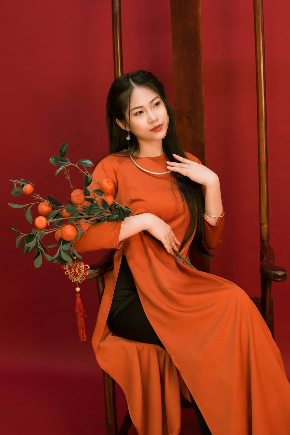 a woman sitting on a chair holding a bouquet of oranges