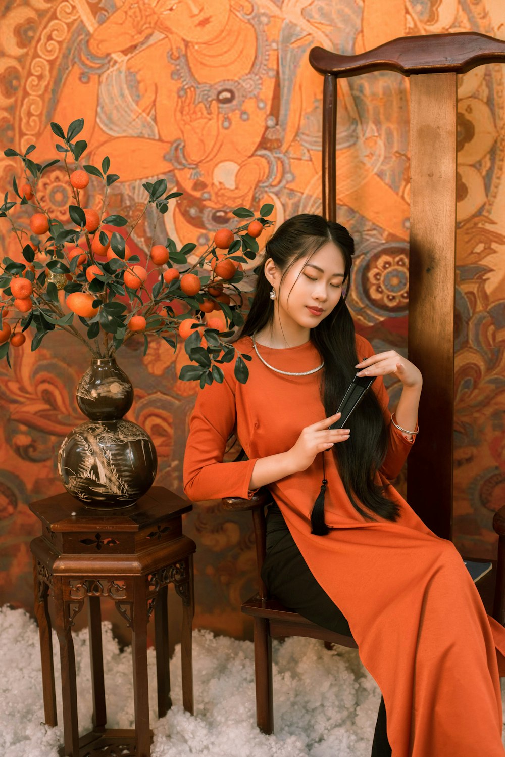 a woman in an orange dress sitting on a chair